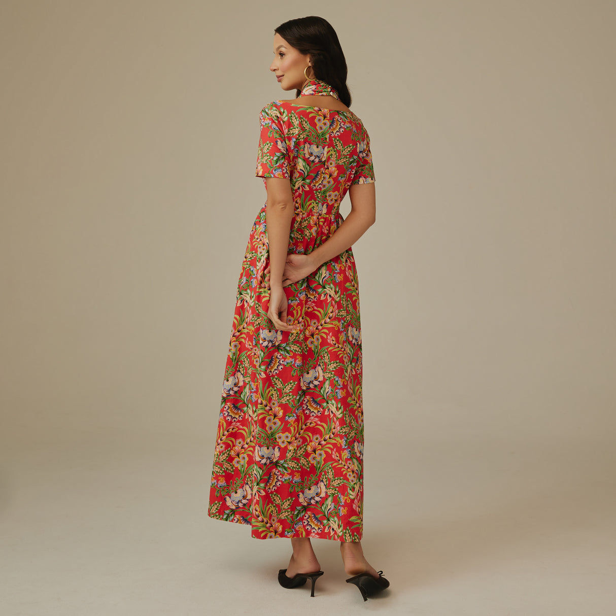 Woman wearing a red floral dress against a beige background